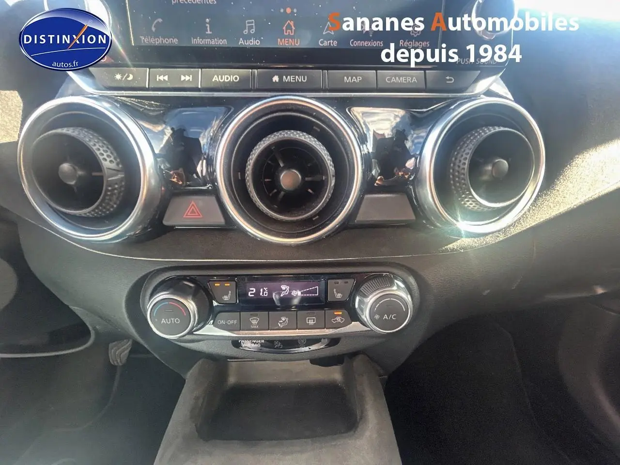Vue rapprochée du tableau de bord du Nissan Juke 2020, mettant en valeur les commandes de climatisation et les aérateurs ronds.
