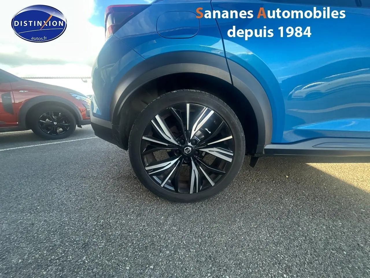 Gros plan sur la roue arrière droite d’un Nissan Juke bleu clair 2020 avec jante alliage noire et argentée.