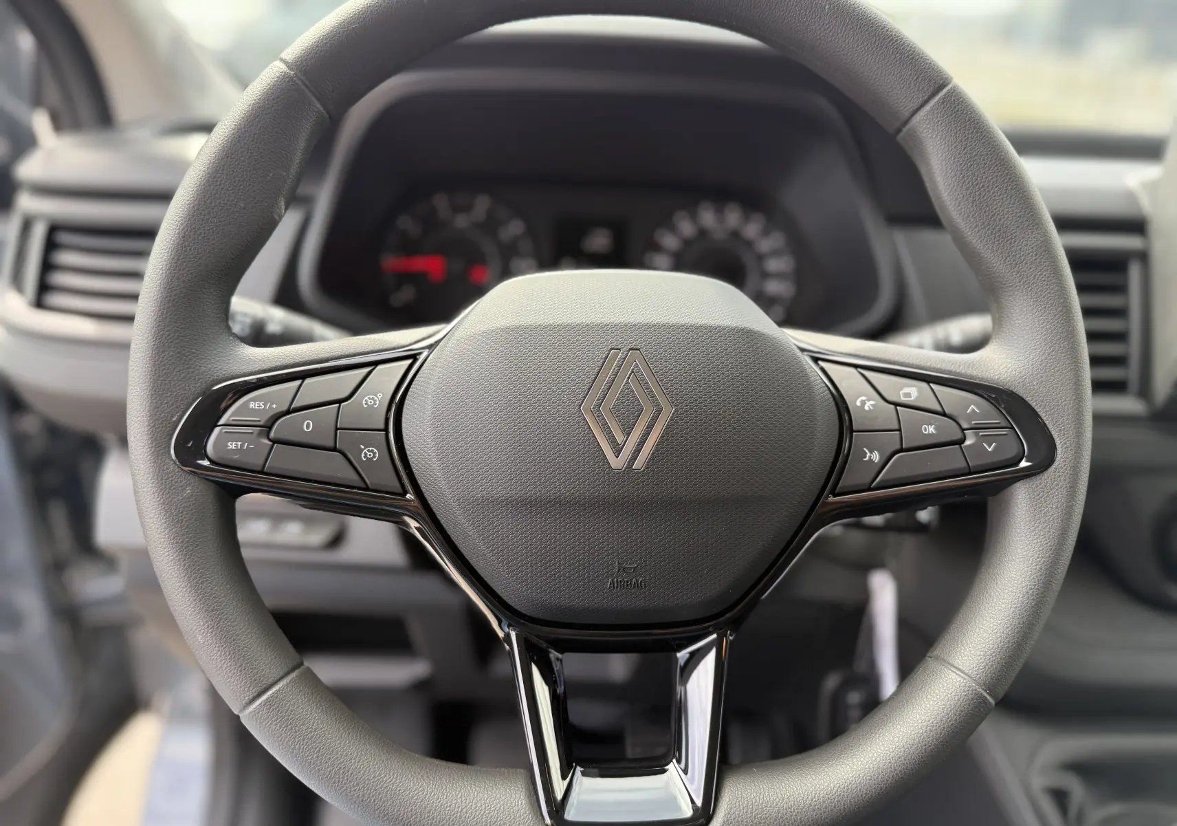 Vue rapprochée du volant multifonction gris du Renault Trafic Combi L2 Grand Evolution 2025 avec commandes intégrées.