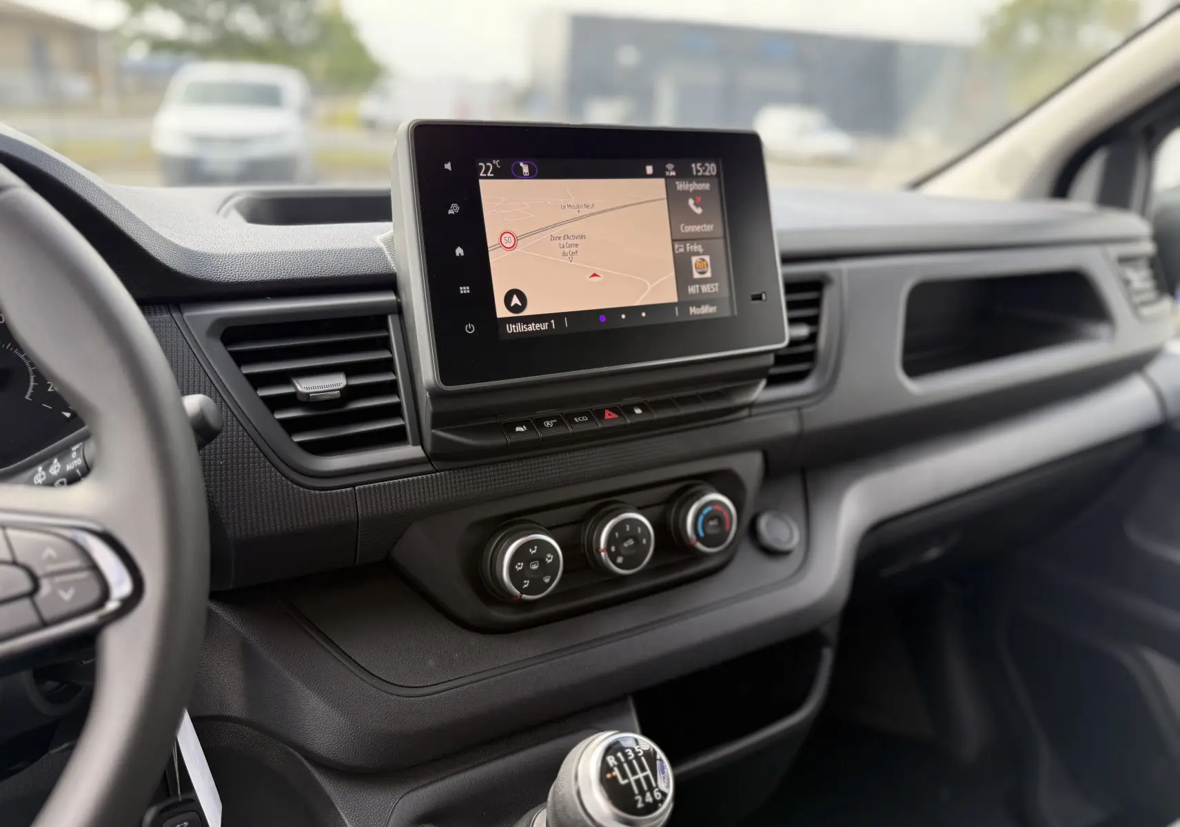 Tableau de bord du Renault Trafic Combi 2025 avec écran tactile, commandes climatisation et levier de vitesses manuel visible côté conducteur.