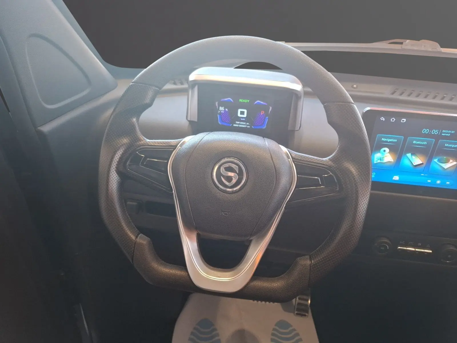 Vue rapprochée du volant noir de la SIMPLICI S1 2025 avec tableau de bord digital et écran tactile bleu.