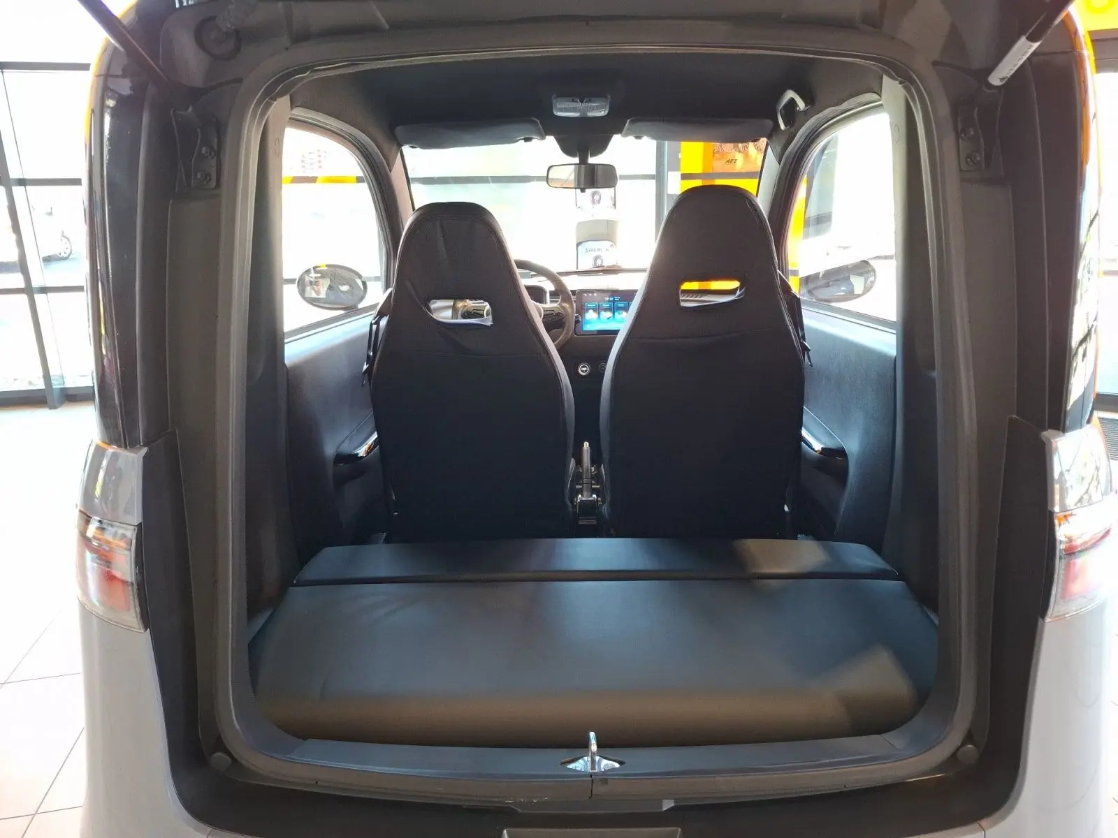 Vue arrière ouverte du SIMPLICI S1 gris perle avec toit noir, montrant les sièges avant et l'intérieur compact électrique.