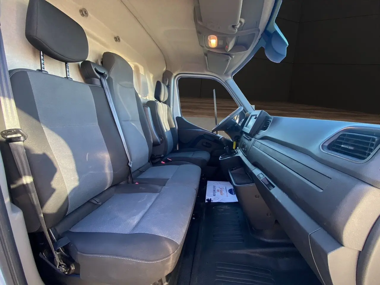 Vue intérieure côté droit du poste de conduite du Nissan Interstar 2022 avec sièges tissu gris et tableau de bord noir.