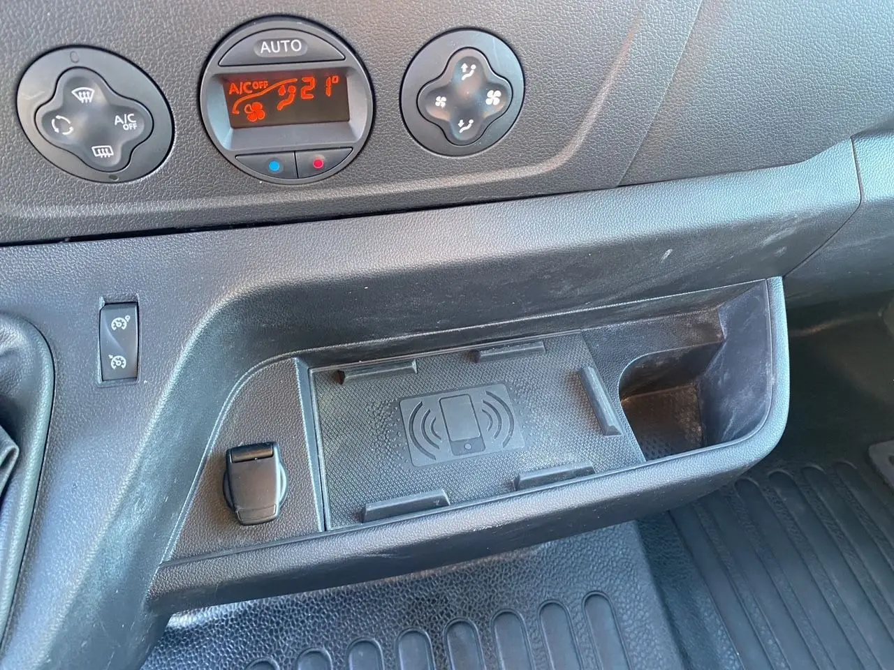 Détail de la console centrale noire du Nissan Interstar 2022 avec commandes de climatisation digitale et espace de recharge sans fil.