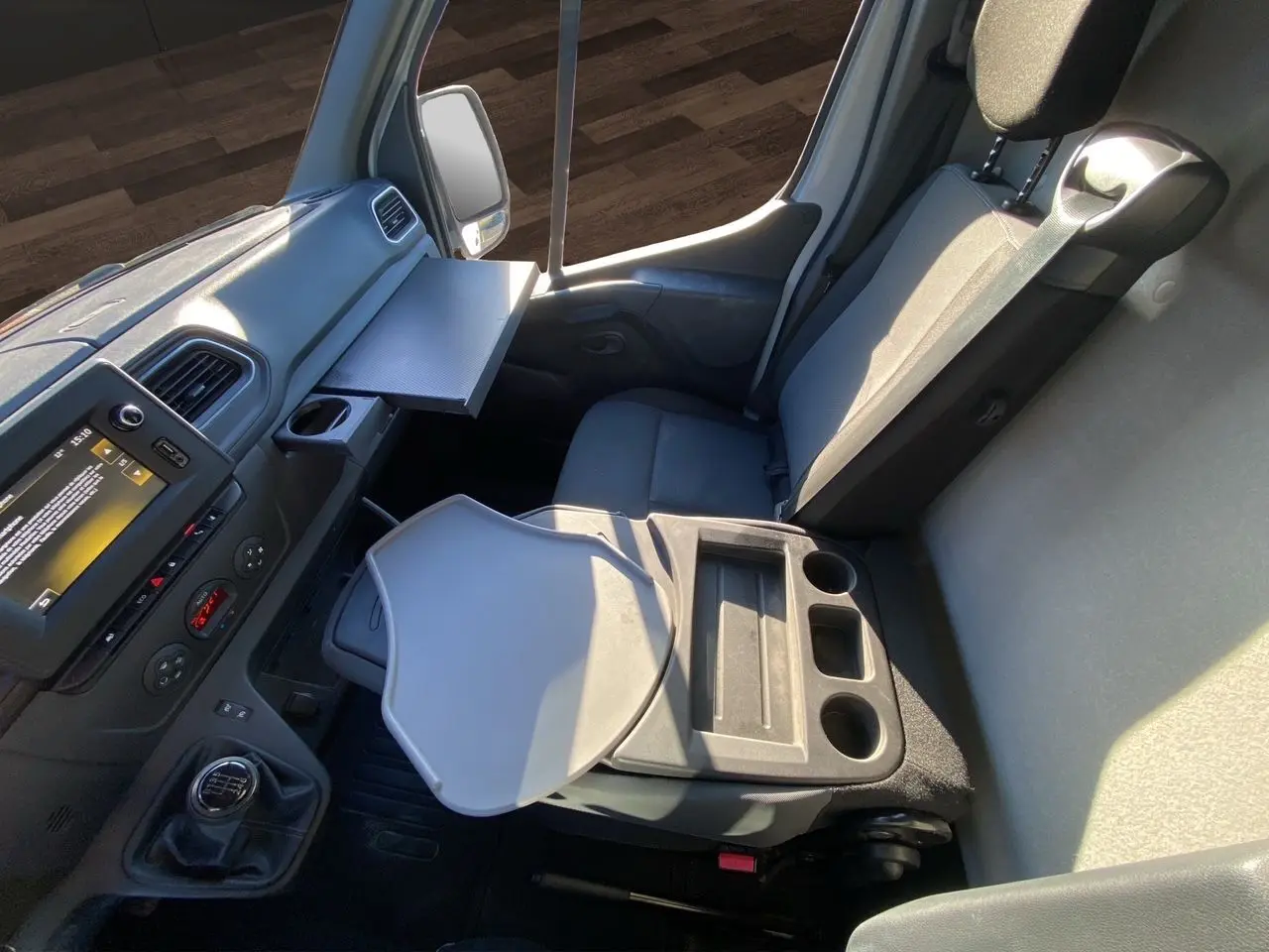 Vue intérieure côté passager du Nissan Interstar blanc 2022, montrant le siège, la console avec porte-gobelets et tablette rabattable.