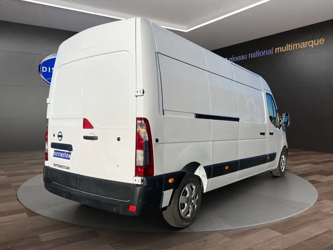 Vue 3/4 arrière droite d’un utilitaire Nissan Interstar blanc, avec caméra de recul et antibrouillards visibles.