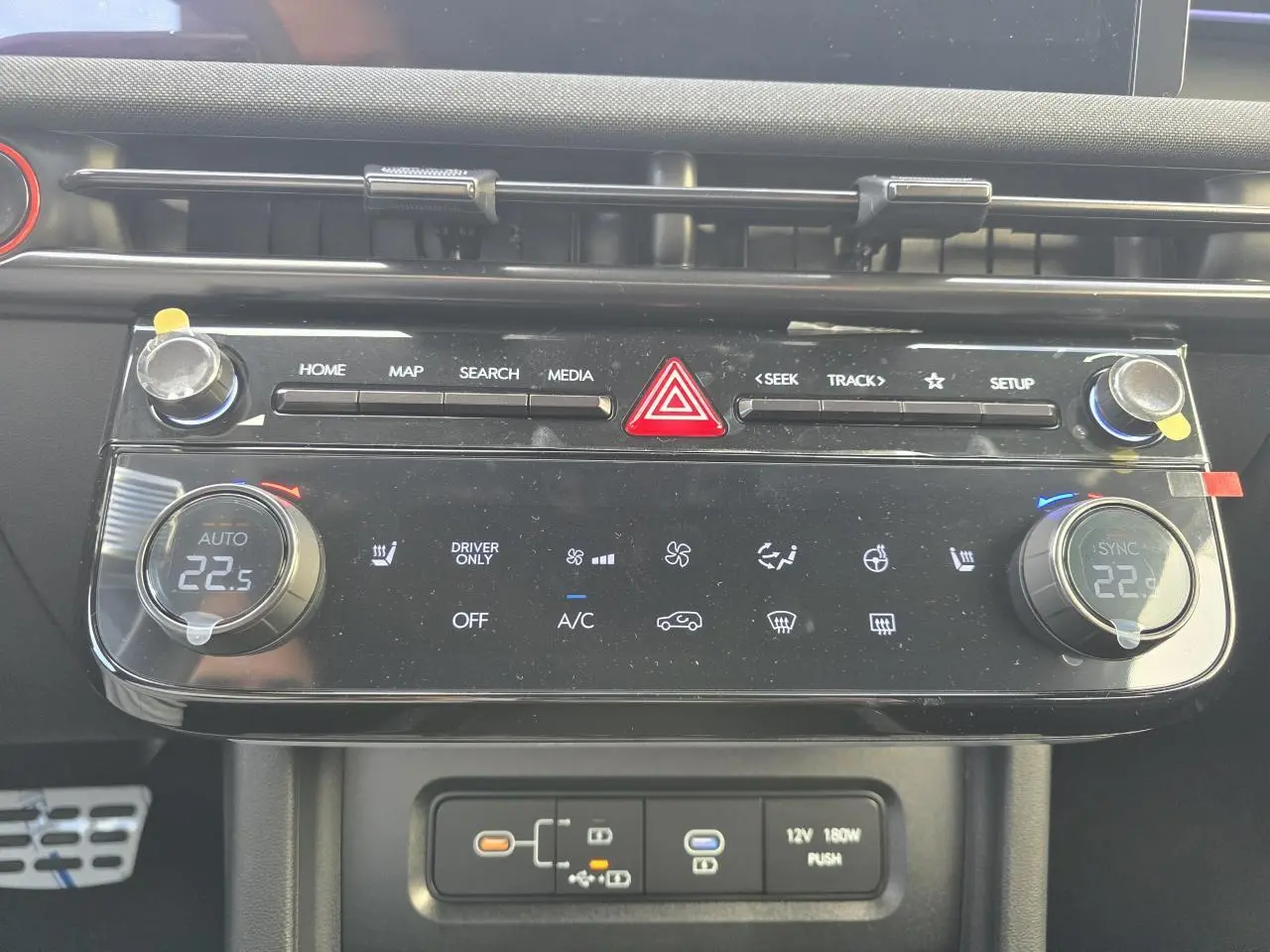 Vue rapprochée de la console centrale noire du Hyundai Tucson 2025, avec commandes climatisation et boutons multimédia.