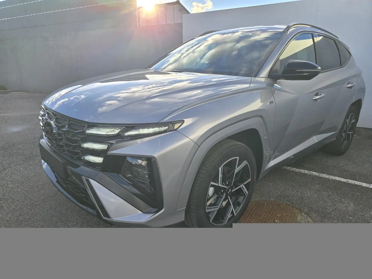 Vue 3/4 avant droit du Hyundai Tucson 2025 en gris métallisé avec calandre noire et jantes alliage 19 pouces N Line.