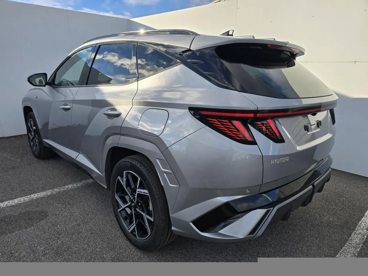 Vue 3/4 arrière droite du Hyundai Tucson 2025 hybride en gris métallisé avec feux arrière LED et jantes alliage 19 pouces N Line.