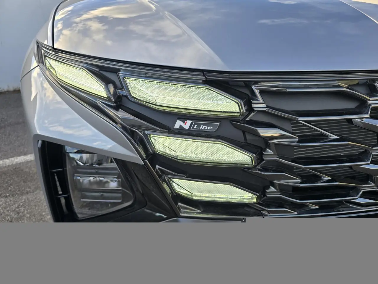 Gros plan sur le phare avant gauche du Hyundai Tucson 2025 Shimmering Silver avec logo N Line et calandre noire.