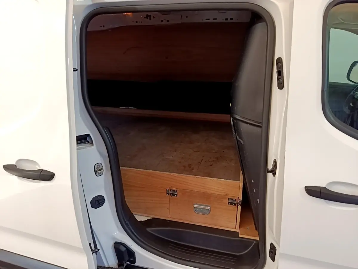 Vue latérale droite du Peugeot Partner blanc 2021 avec porte coulissante ouverte montrant l'espace de chargement en bois.