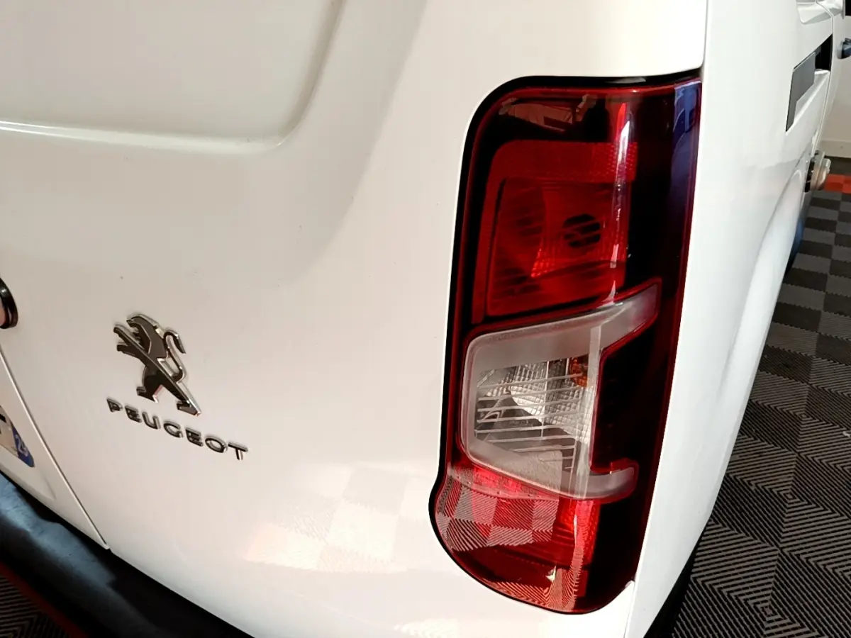 Vue rapprochée arrière droite du Peugeot Partner blanc, mettant en valeur le feu arrière et le logo Peugeot.