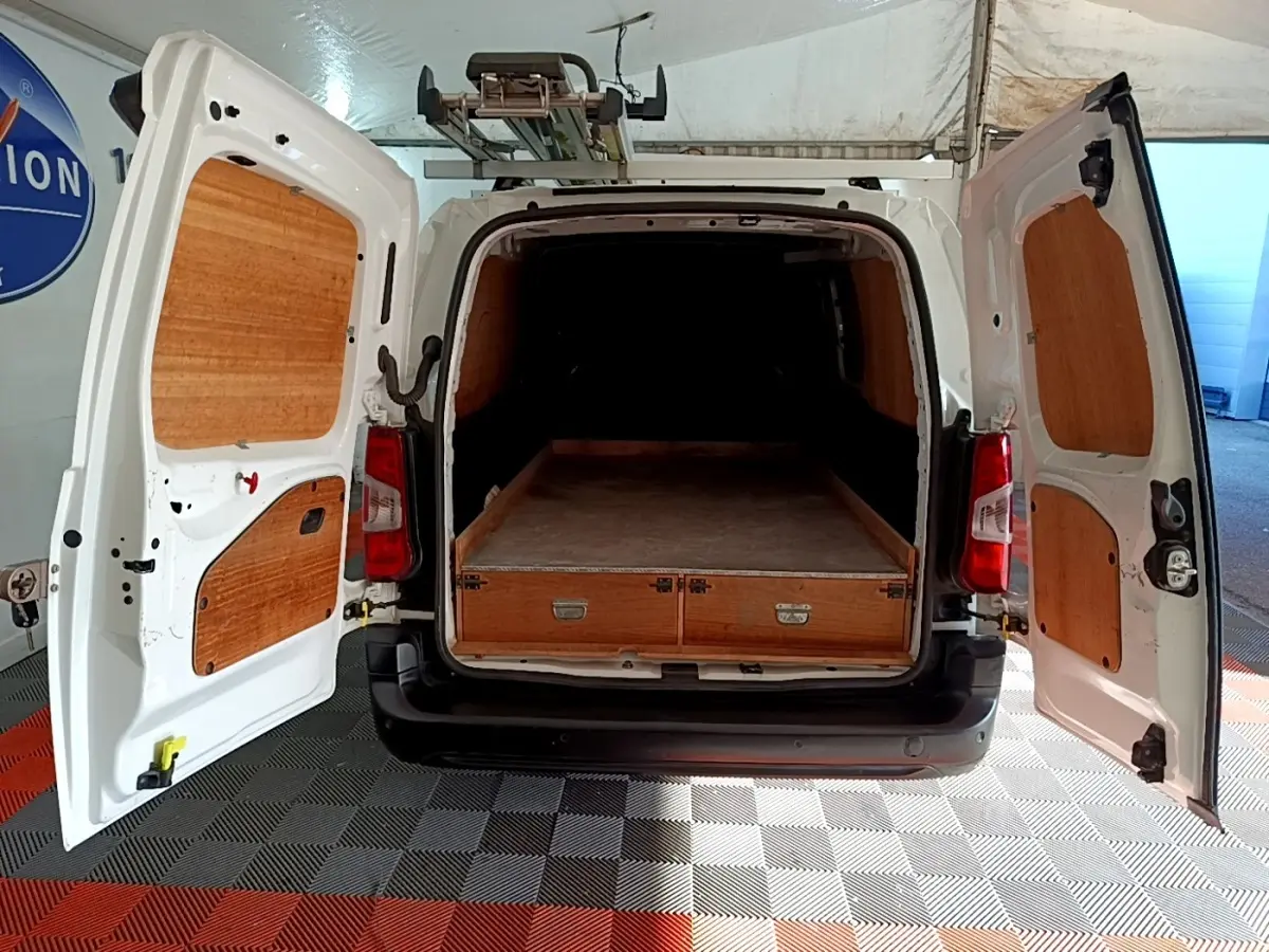 Vue arrière du Peugeot Partner blanc 2021 avec portes ouvertes et aménagement bois dans l’espace de chargement.