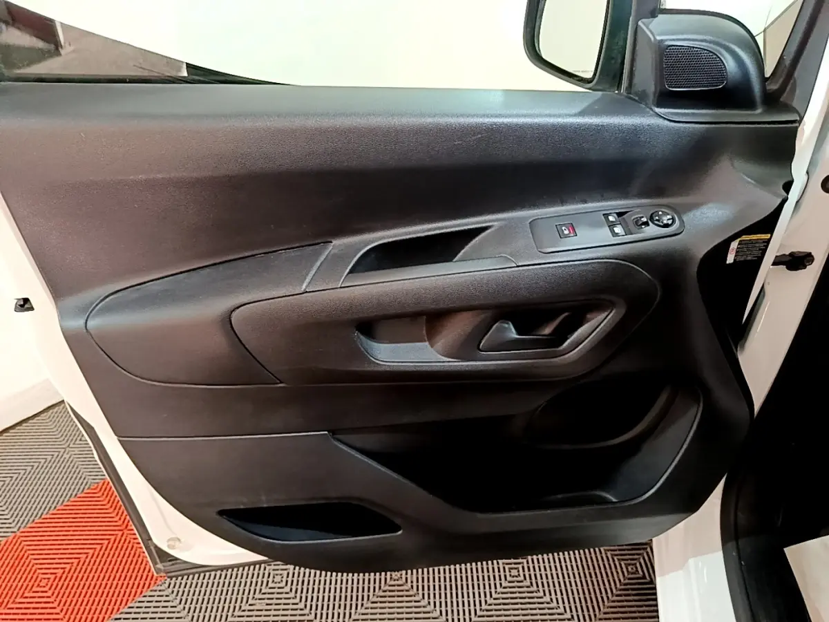 Vue rapprochée de la porte avant gauche noire du Peugeot Partner blanc, avec commandes électriques et haut-parleur intégré.
