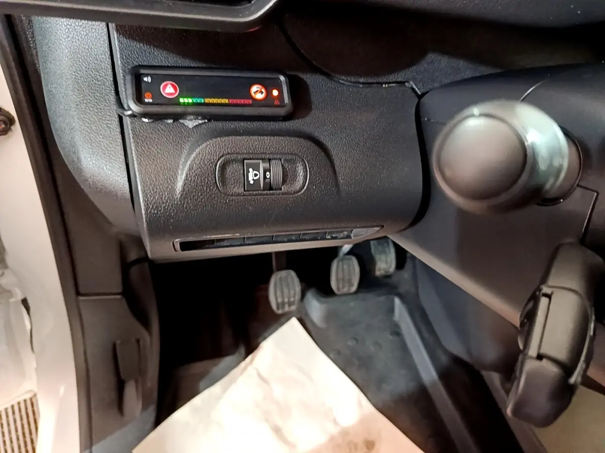 Vue intérieure côté conducteur du Peugeot Partner blanc 2021, montrant les pédales et commandes sous le tableau de bord.