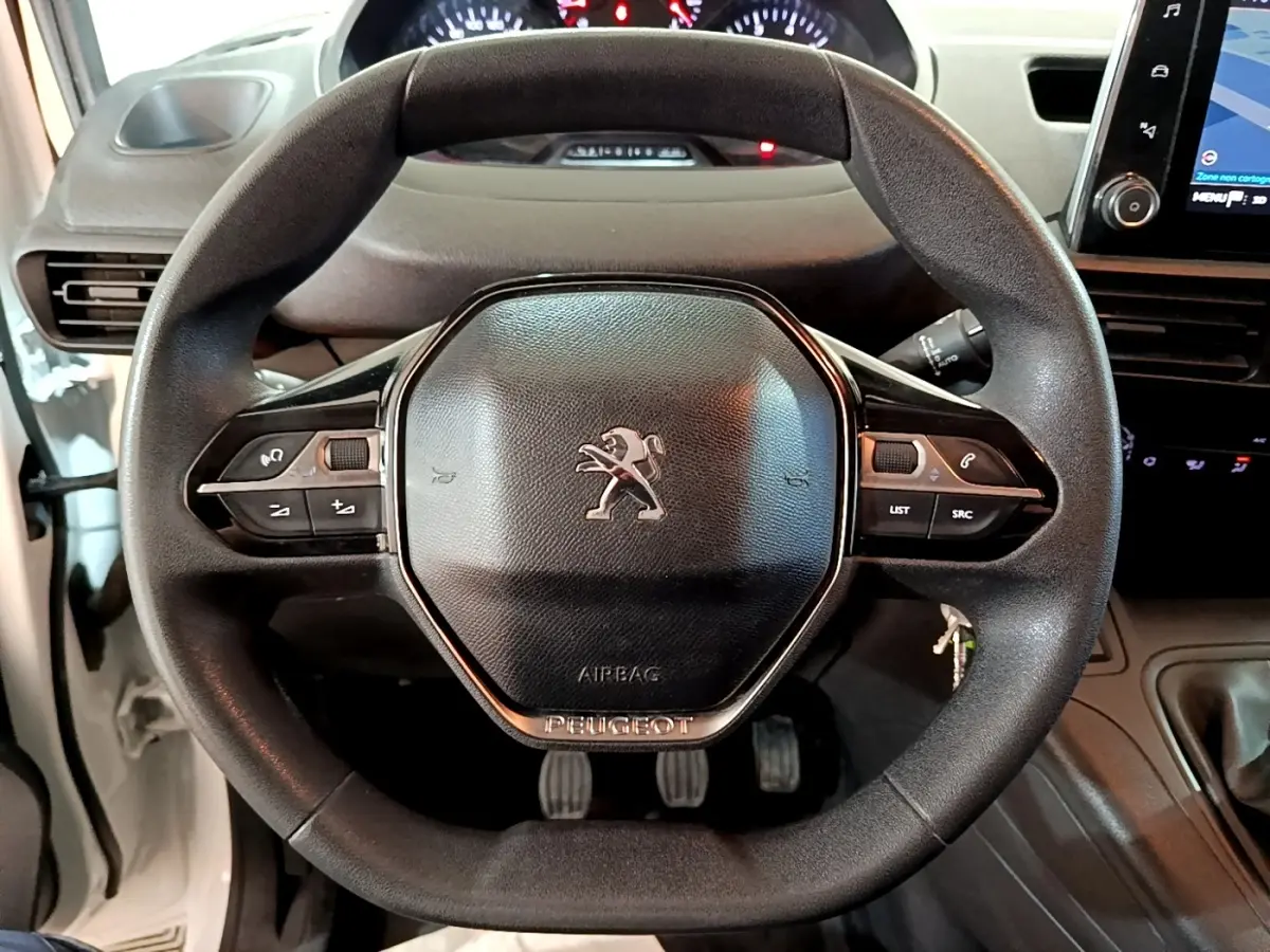 Vue rapprochée du volant noir du Peugeot Partner blanc 2021 avec commandes intégrées et tableau de bord tactile.