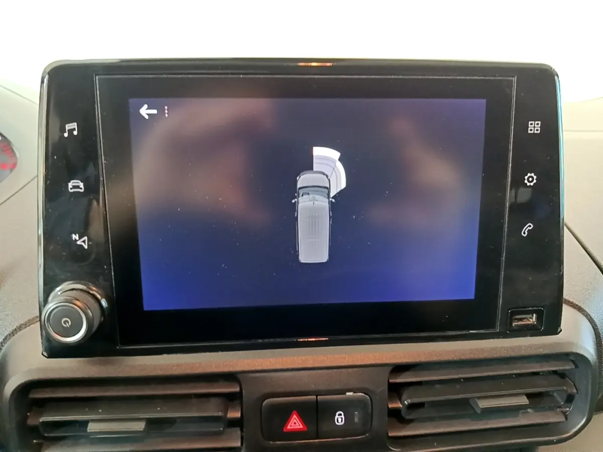 Écran tactile central montrant l'aide au stationnement du Peugeot Partner blanc, vue intérieure du tableau de bord.