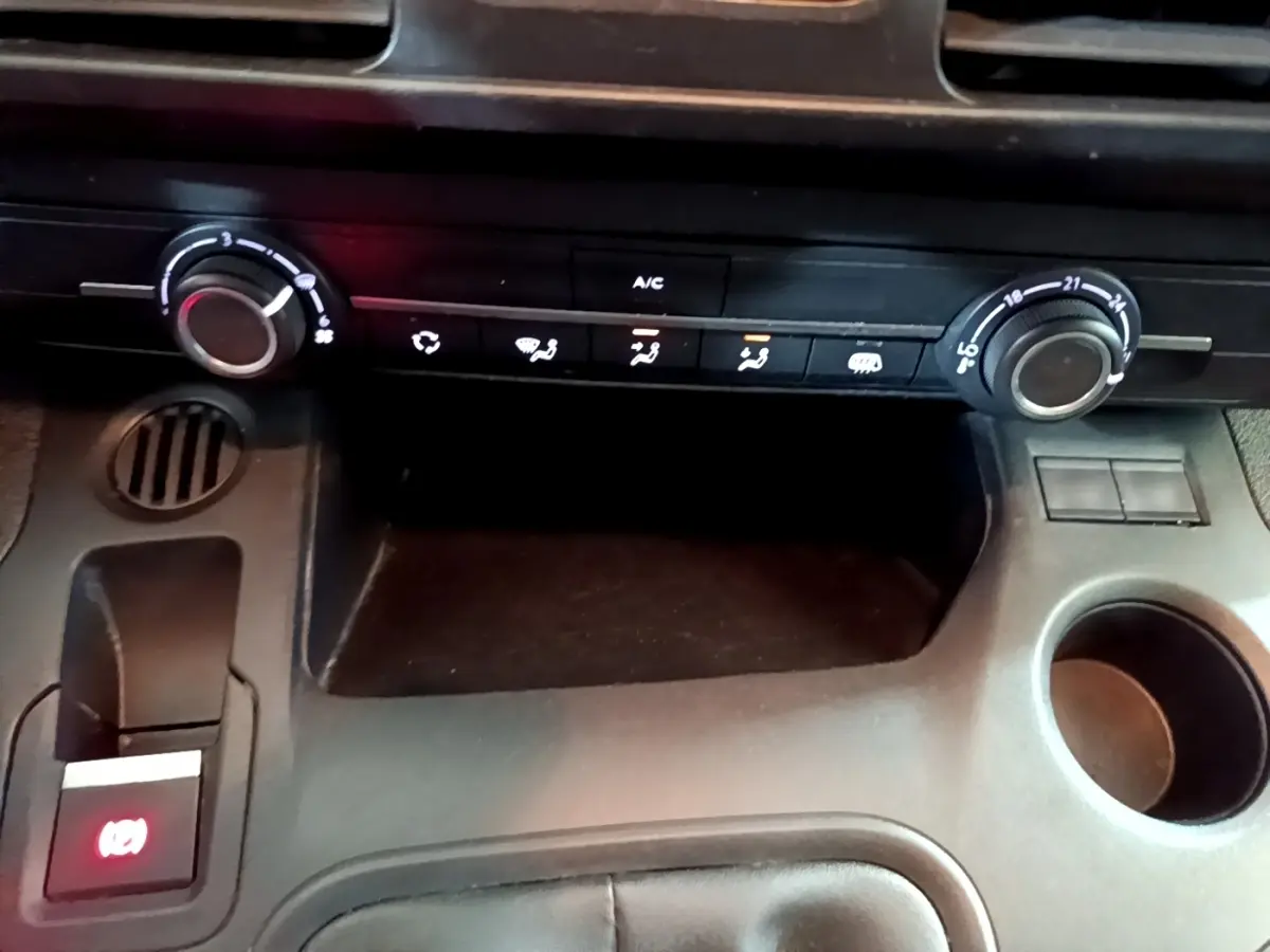 Vue rapprochée de la console centrale noire du Peugeot Partner 2021, montrant les commandes de climatisation et frein à main électrique.