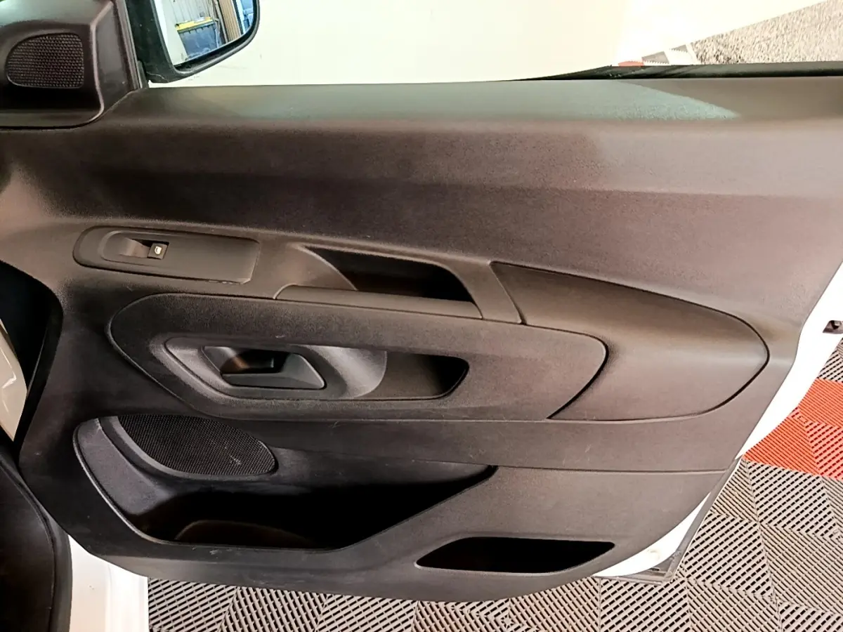 Vue rapprochée de la porte intérieure côté conducteur du Peugeot Partner blanc, avec commandes de fenêtre et rangement.