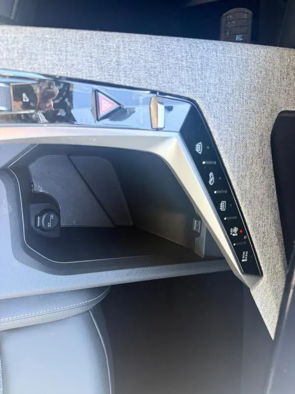Gros plan sur la console centrale du Peugeot 3008 Hybrid gris, montrant les commandes de chauffage et prise 12V.