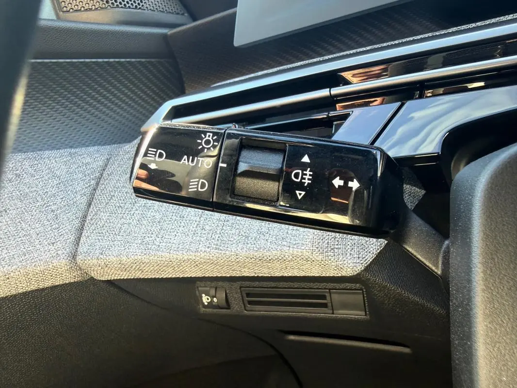Gros plan sur la commande des feux automatique et clignotants dans l’habitacle gris du Peugeot 3008 Hybrid 145 e-DCS6 Allure.