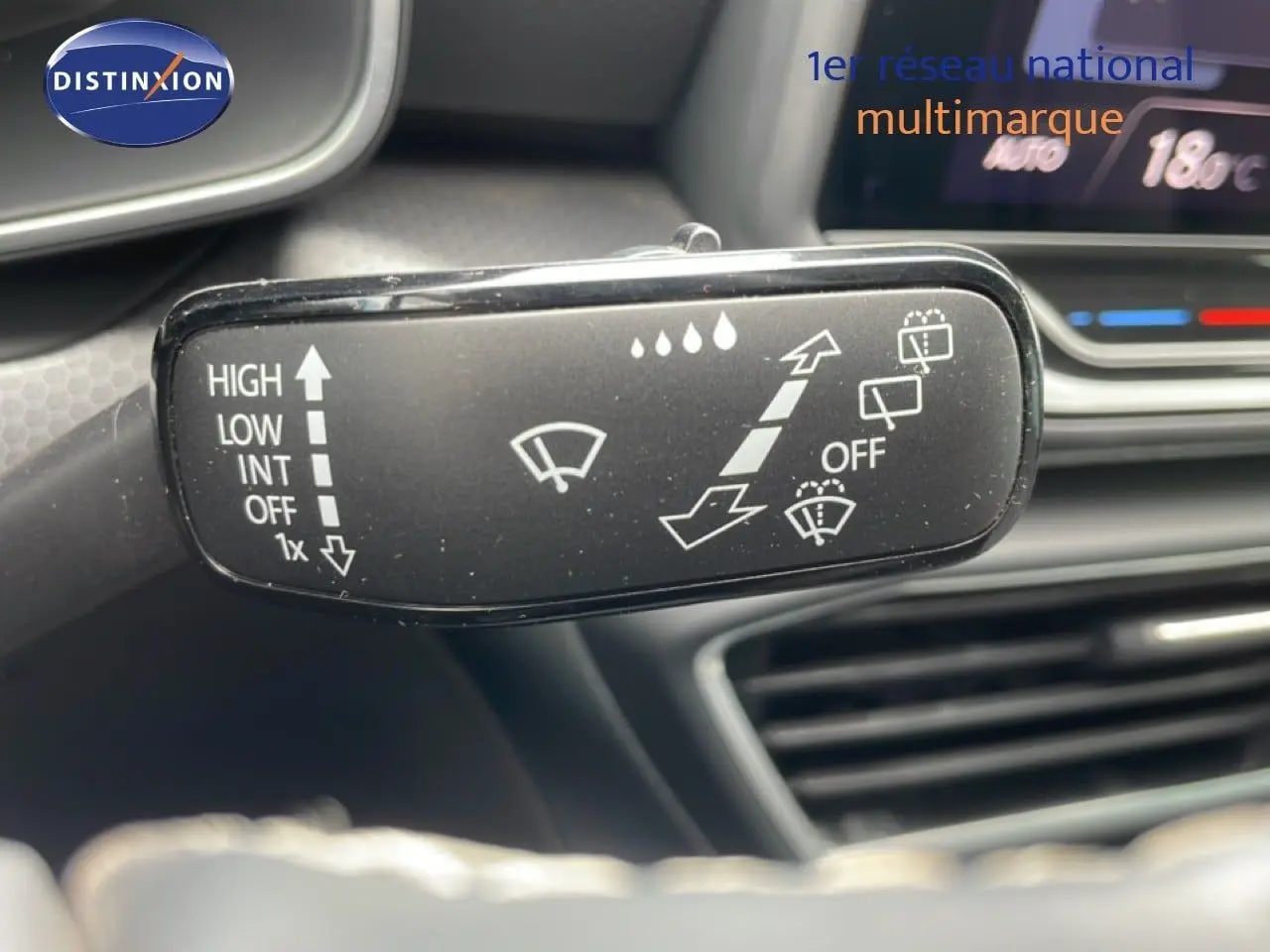 Gros plan sur la commande d’essuie-glace du SEAT LEON 2025 blanc neige métal, avec tableau de bord en arrière-plan.