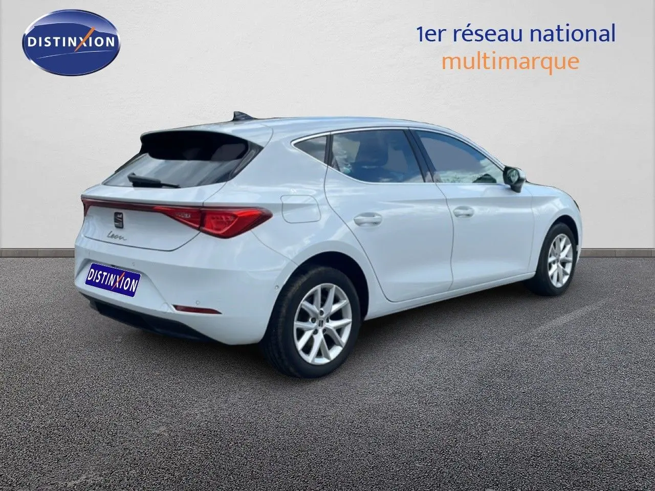 Vue 3/4 arrière droite d'une SEAT Leon blanc neige métal avec feux arrière allongés et jantes alliage.