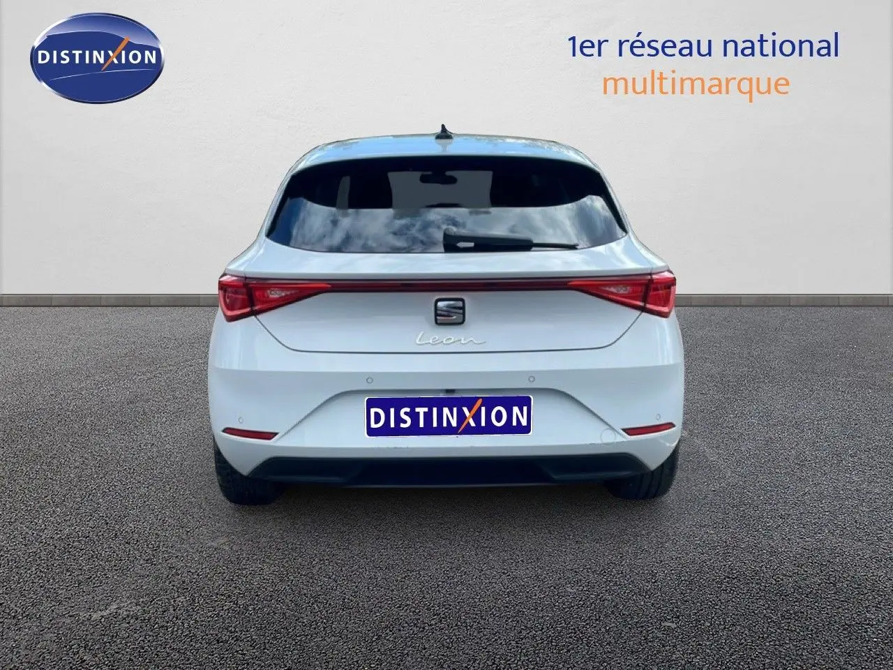 Vue arrière d'une SEAT Leon blanc neige métal 2025 avec feux LED reliés par une bande lumineuse rouge.