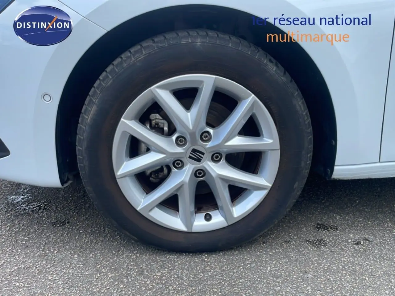 Gros plan sur la roue avant gauche d'une SEAT LEON blanc neige métal avec jante alliage à 5 doubles branches.