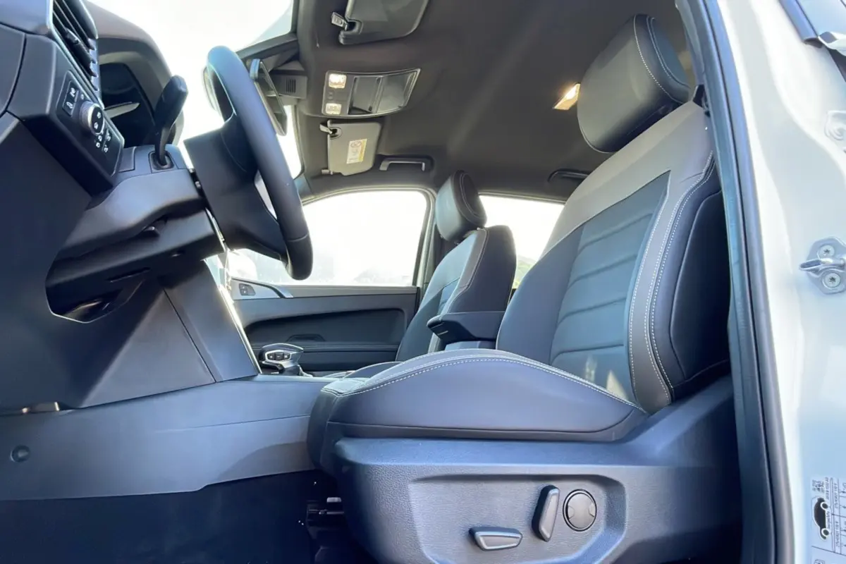 Vue intérieure côté conducteur du Volkswagen Amarok Simple Cabine blanc, sièges cuir gris avec surpiqûres blanches.