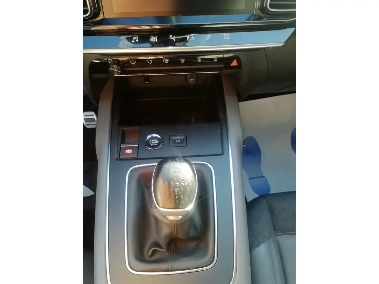 Vue plongeante sur la console centrale du Citroën C5 Aircross gris, mettant en valeur le levier de vitesse manuel et les commandes environnantes.