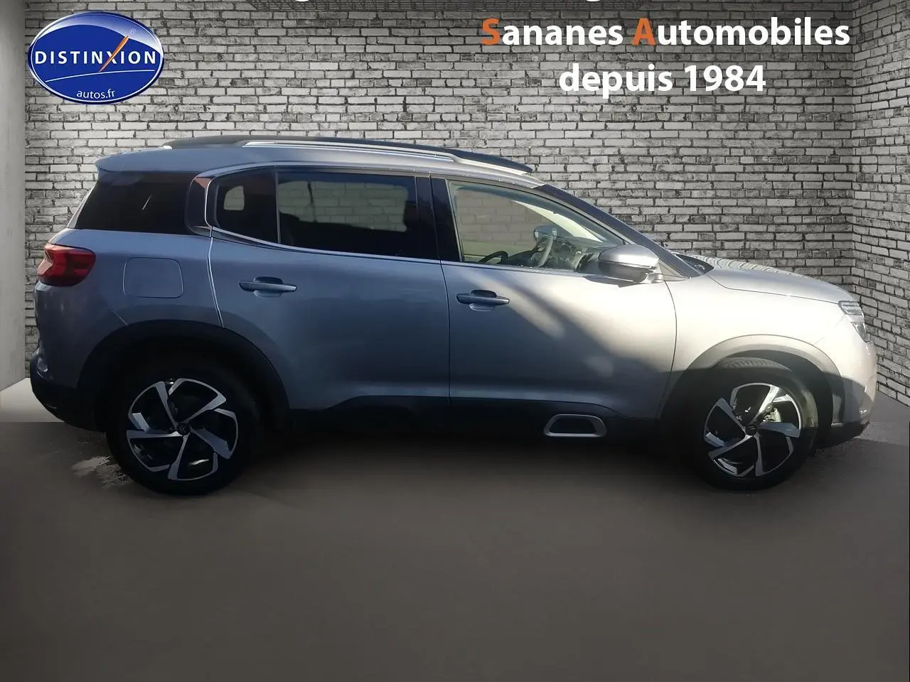 Profil côté gauche d’un Citroën C5 Aircross gris métallisé 2019 avec jantes alliage et barres de toit bi-ton.