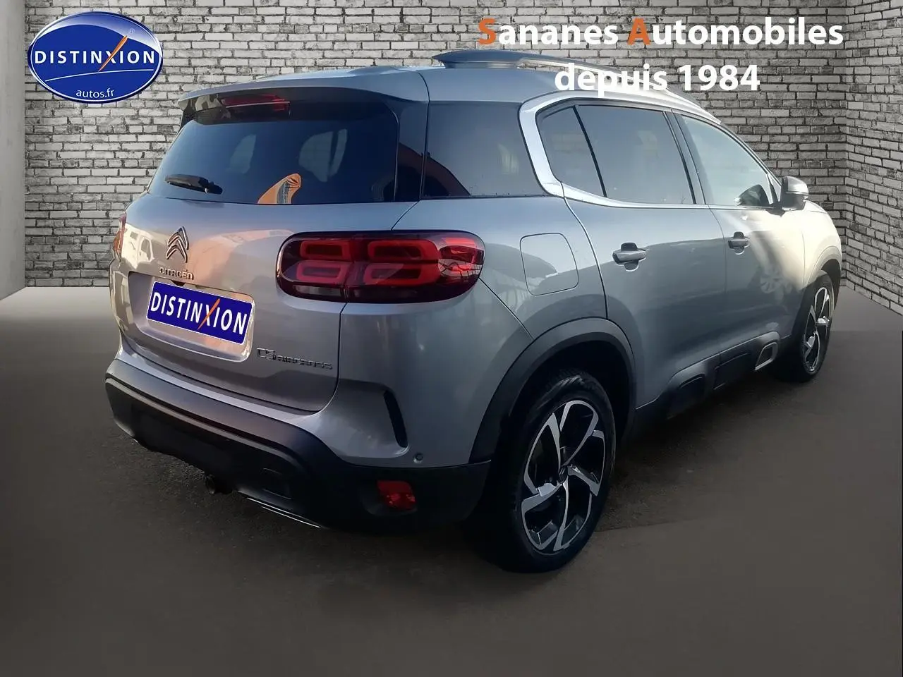 Vue 3/4 arrière droite d’un Citroën C5 Aircross gris métallisé avec jantes alliage 18 pouces et vitres teintées.