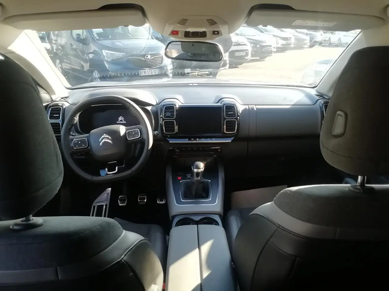 Vue intérieure avant du Citroën C5 Aircross gris, volant multifonction, tableau de bord moderne et levier de vitesse manuel.