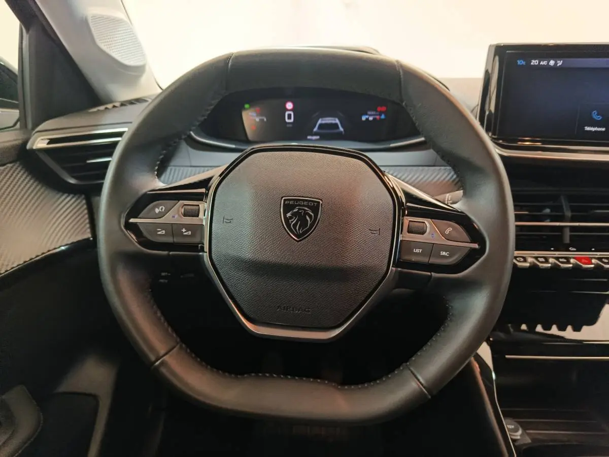Volant cuir noir de la Peugeot 208 PureTech 100 S&S Allure 2025 avec tableau de bord digital et écran tactile central.