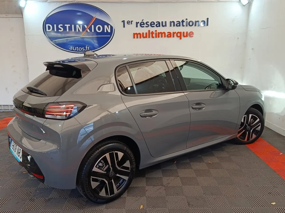 Peugeot 208 PureTech 100 S&S Allure gris foncé vue 3/4 arrière droit en intérieur showroom.