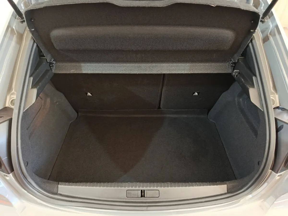 Coffre ouvert d'une Peugeot 208 gris foncé, vue de dessus montrant l'espace de chargement vide et propre.