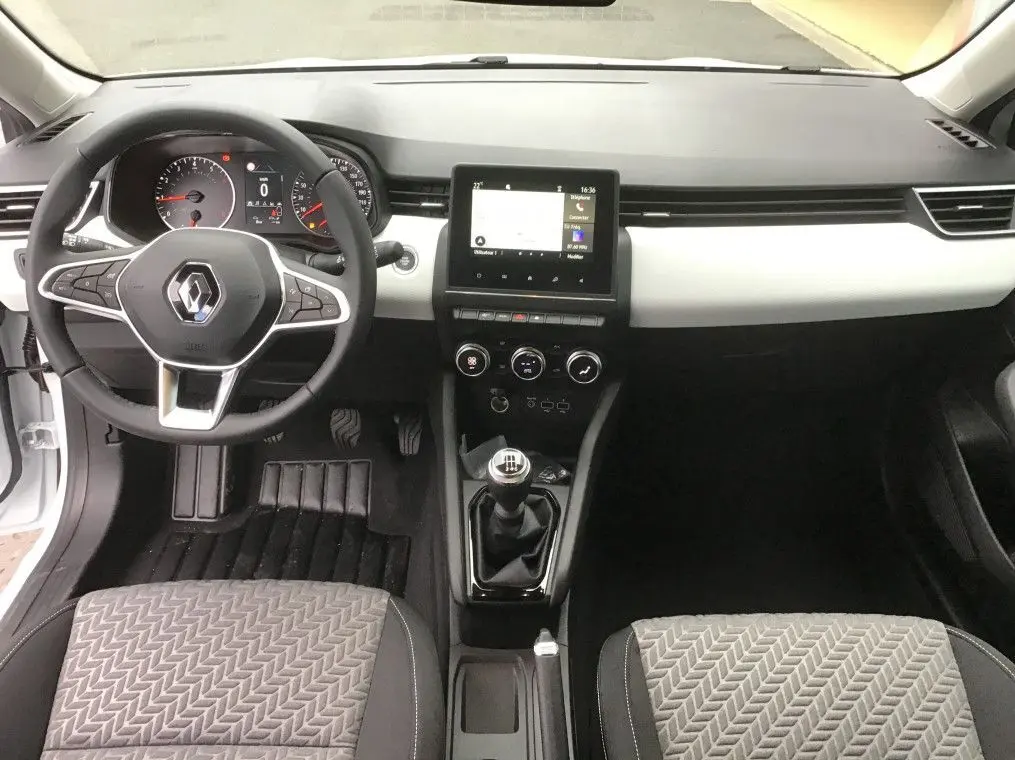 Vue intérieure avant de la Renault Clio V 1.0 TCE 90 Evolution avec tableau de bord noir et blanc et levier de vitesse manuel.