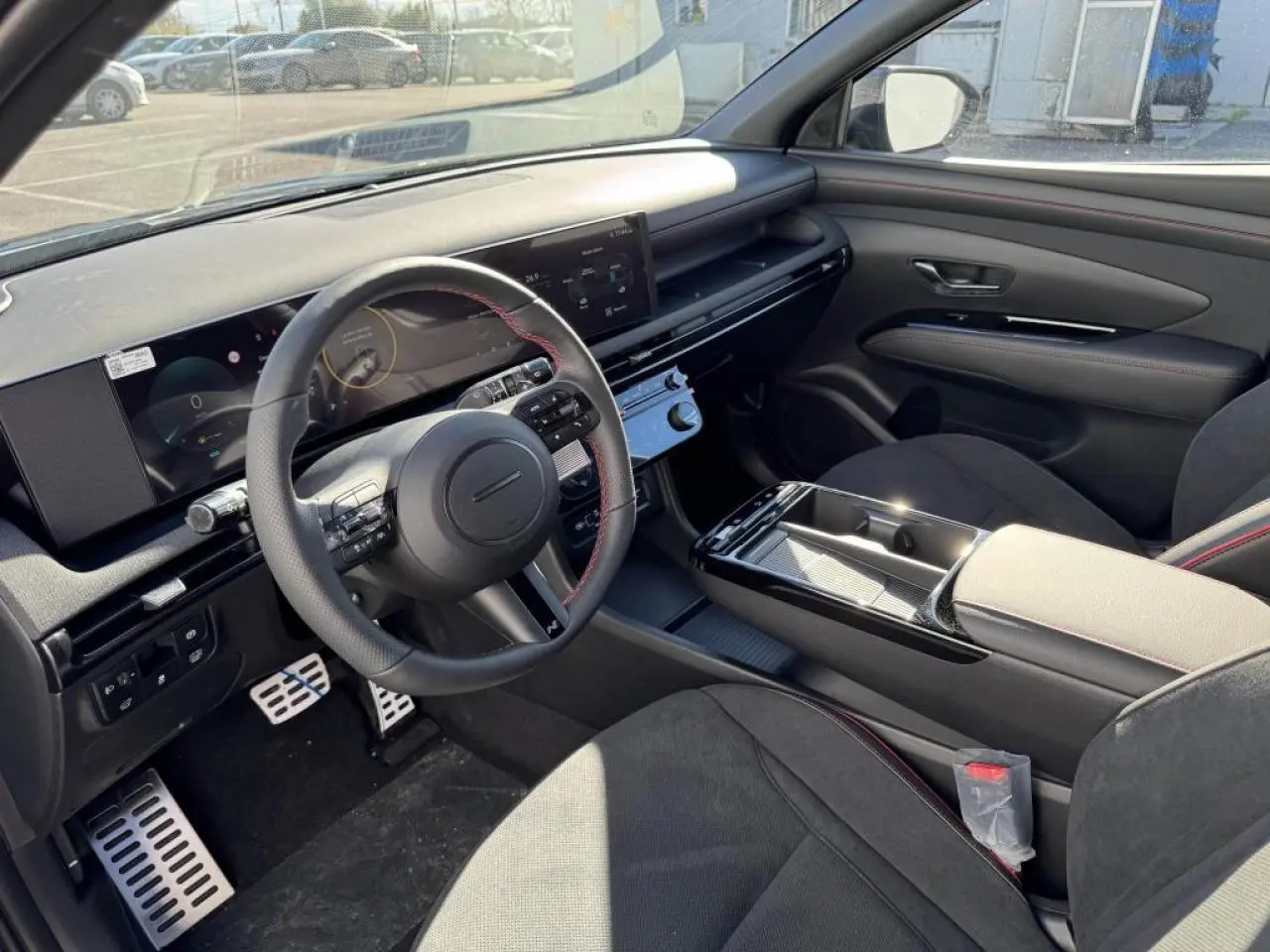 Vue intérieure côté conducteur du Hyundai Tucson 2025, avec volant cuir N Line à surpiqûres rouges et tableau de bord numérique.