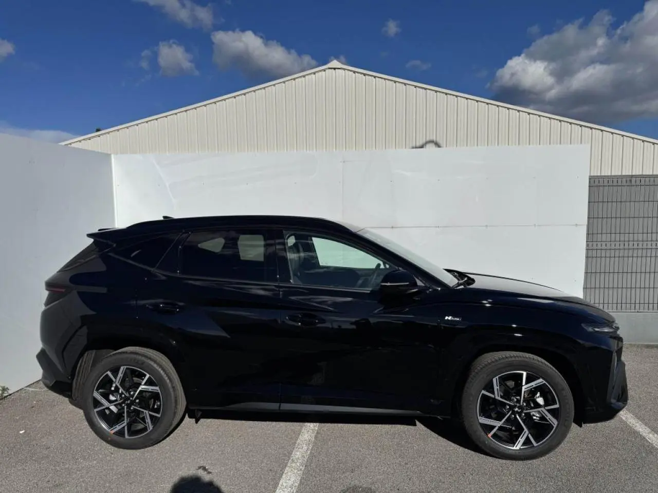 Vue latérale droite du Hyundai Tucson noir Abyss Metal avec jantes alliage 19'' N Line et vitres surteintées.