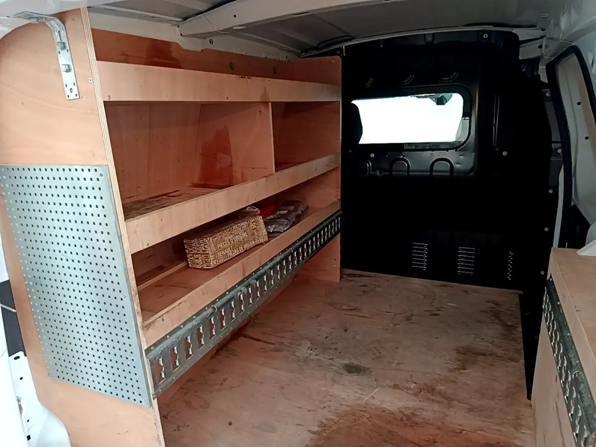 Intérieur du Renault Express blanc vu de l’arrière, montrant les étagères en bois et la cloison pleine vitrée.