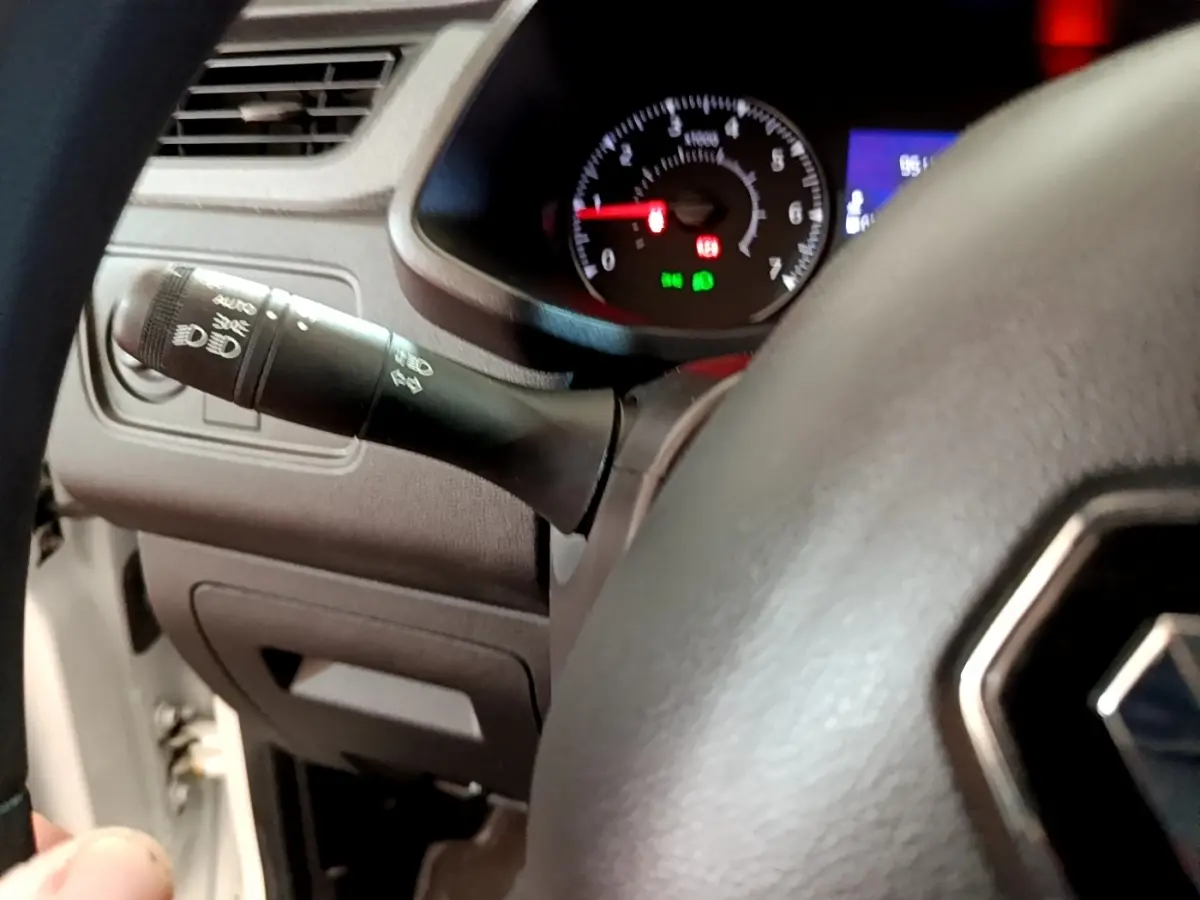 Gros plan sur le volant et la commande des phares du Renault Express blanc, tableau de bord avec compte-tours visible.