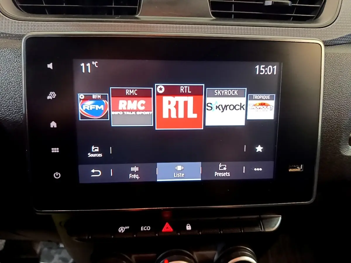 Écran tactile central du Renault Express blanc, affichant les stations radio, vue intérieure frontale.