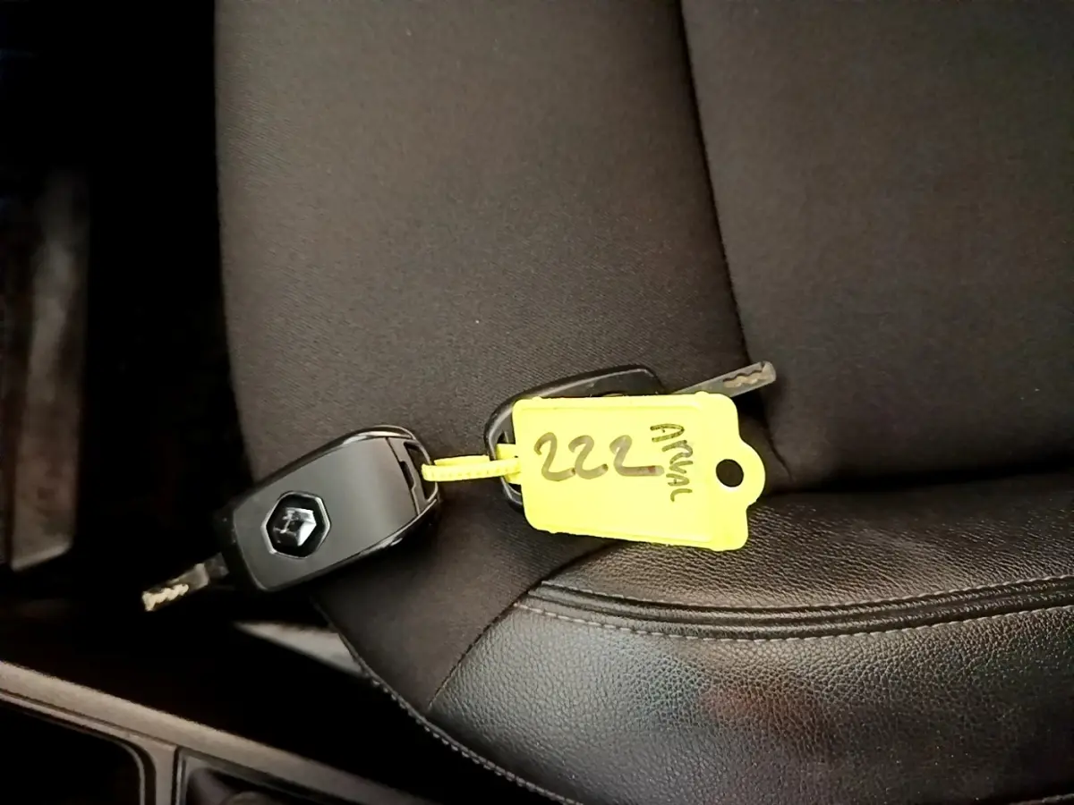 Clé de voiture Renault Express blanche posée sur un siège noir, vue rapprochée de l'intérieur.