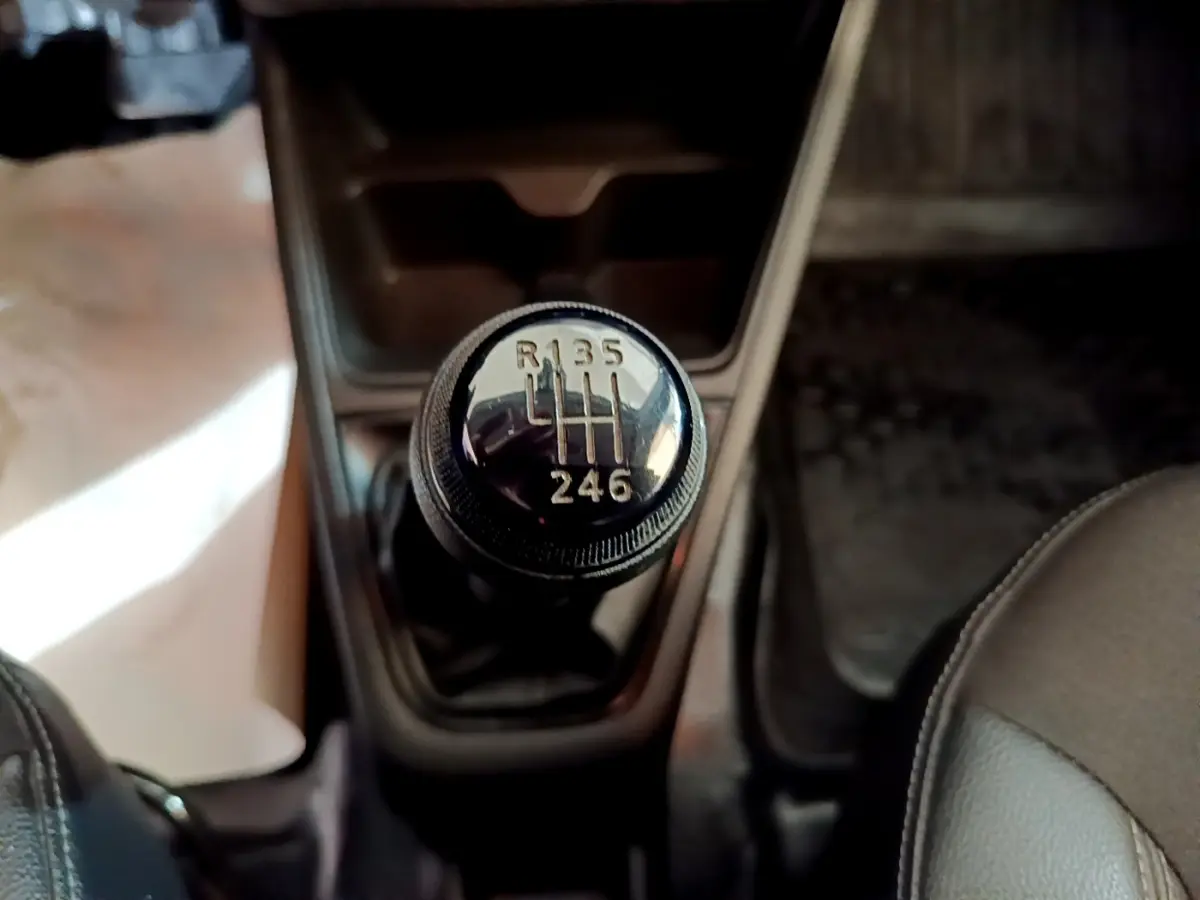 Gros plan sur le levier de vitesses manuel noir de la Renault Express Confort 2021, intérieur sombre.