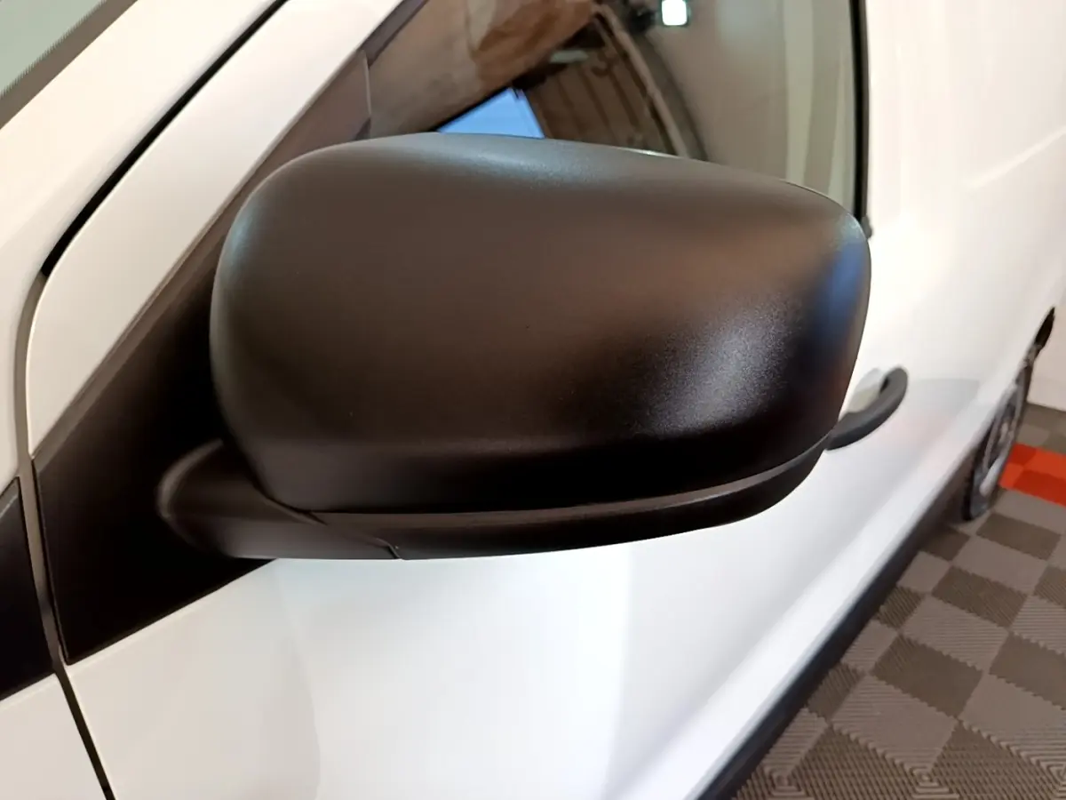Gros plan sur le rétroviseur noir côté gauche du Renault Express blanc, avec poignée de porte visible.
