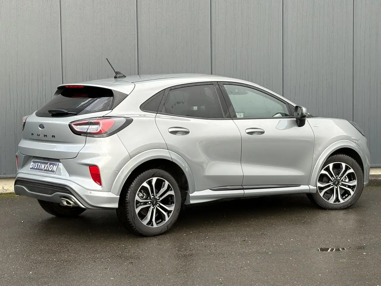 Ford Puma gris Solar vue 3/4 arrière droit, avec jantes alliage 17 pouces et hayon électrique visible.