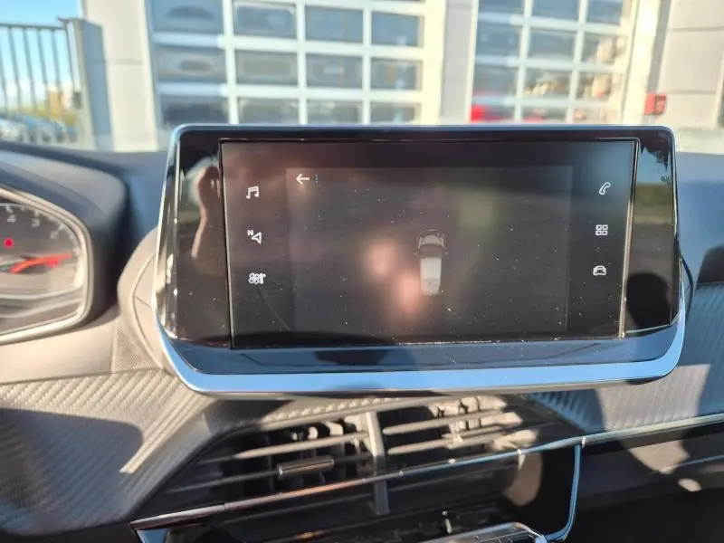 Écran tactile central du tableau de bord de la Peugeot 208 gris Artense, affichant l'aide au stationnement.