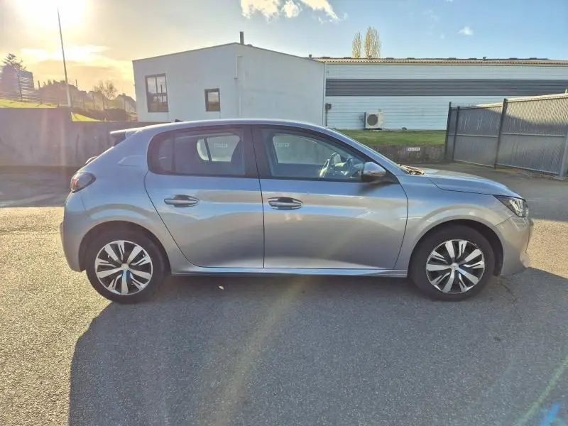 Profil côté droit d'une Peugeot 208 gris Artense 2020, avec jantes alliage et vitres teintées, stationnée en extérieur.