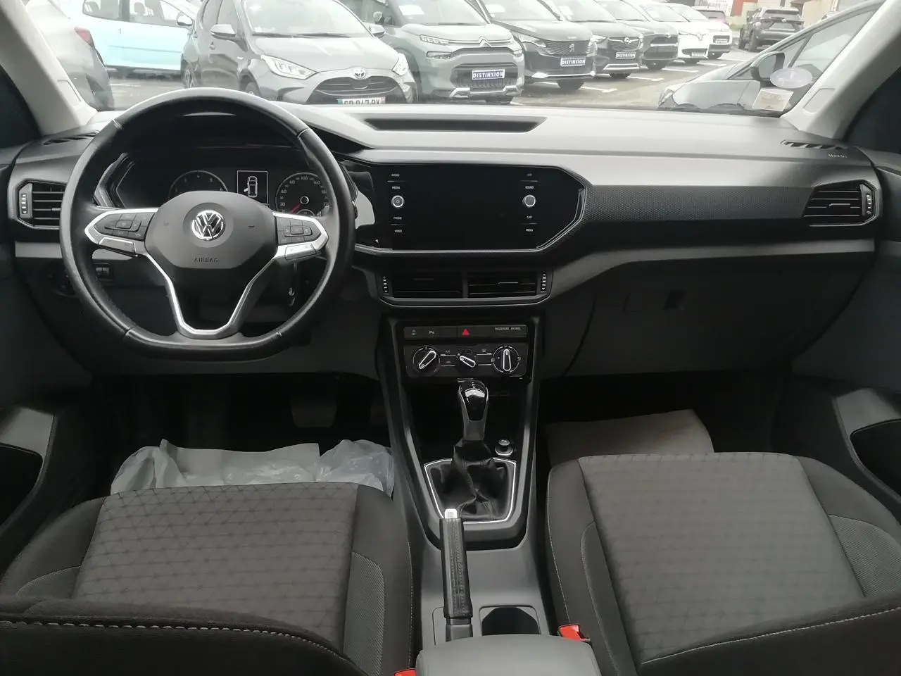 Vue intérieure avant du Volkswagen T-Cross 2020, tableau de bord noir avec écran tactile et volant multifonction.